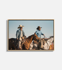 Framed wall art of cowboys riding horses under clear sky, rustic statement decor